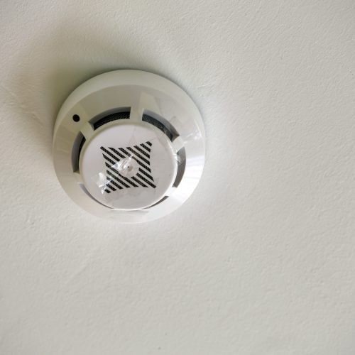 Smoke detector of fire alarm device on copy space background of white ceiling.